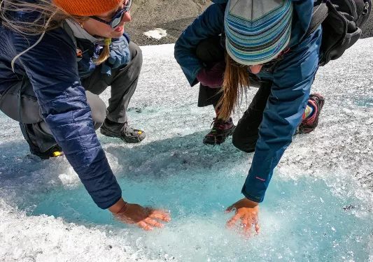 Two guests with their hands in a small ice pool.