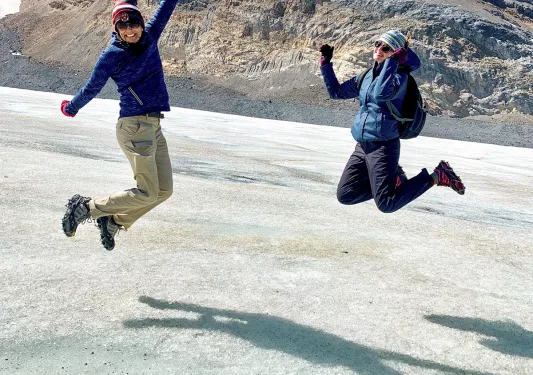 Two guests jumping in air on ice shelf.
