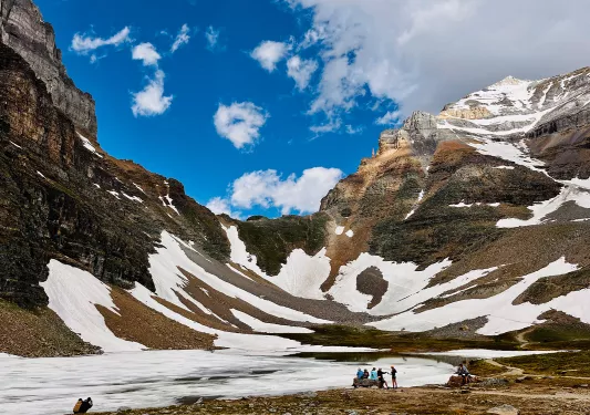 Group of guests below snowy mountain range.