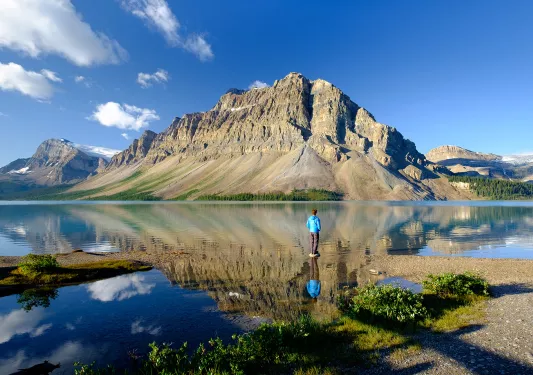 Wide shot of large lake, guest looking towards craggy mountains.