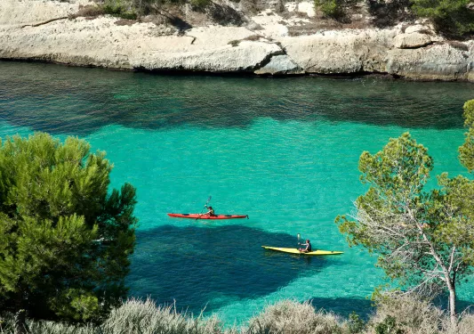 Wide shot of two guests kayaking through blue water.