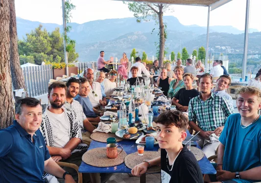 Large group of guests at long table, looking at camera.