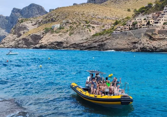 Guests on large dinghy, golden cliffs behind them.