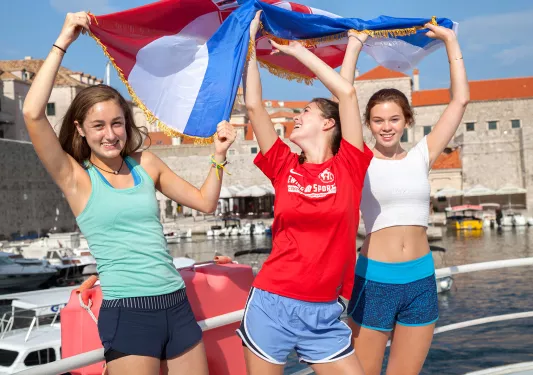 Three teenage girls waving the flag of Croatia