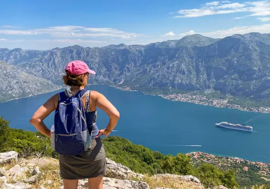 Guest on hilltop, overlooking large, mountain ringed lake or inlet.