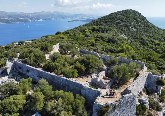 Bird's eye shot of guests among hilltop castle ruins.