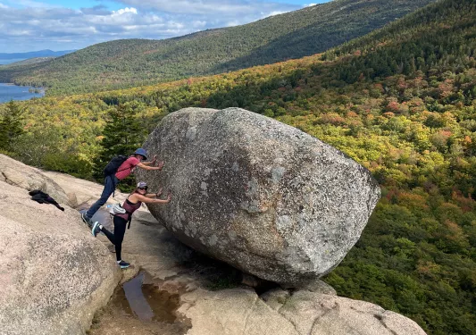 Two guests pretending to push large boulder off a cliff.