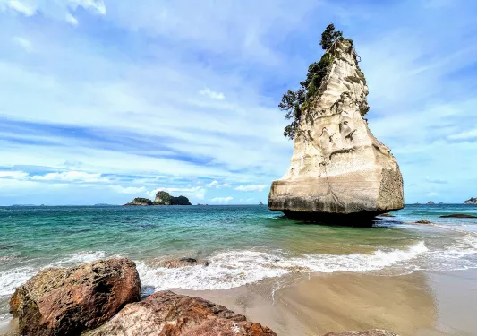 Tall rock formation by the beach in New Zealand