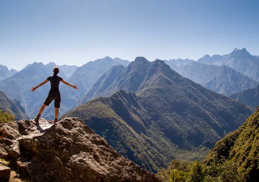 Guest on mountaintop overlooking sharp, craggy mountains.