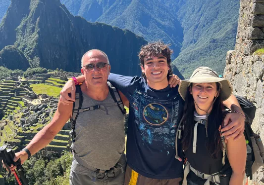 Three guests with hiking poles posing, Machu Picchu behind them.