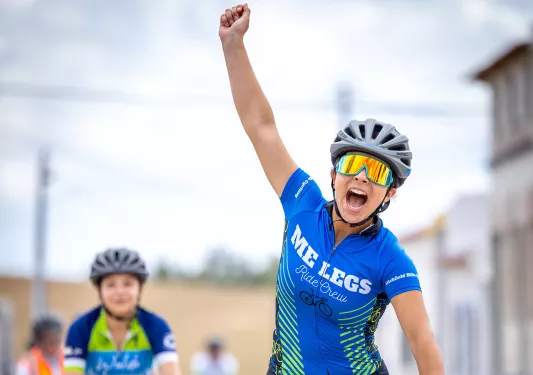 Woman raising her arm in triumph while biking