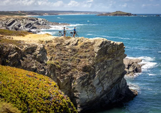 Two bikers resting on a cliff overlooking the sea