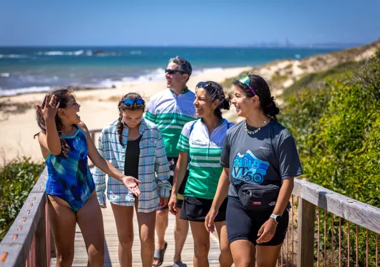 Family walking up wooden steps leading away from a sandy beach