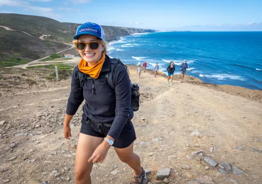 Woman hiking along the beach with the ocean in the background
