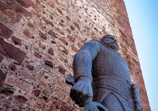 Looking up at an old stone facade and statue holding a sword