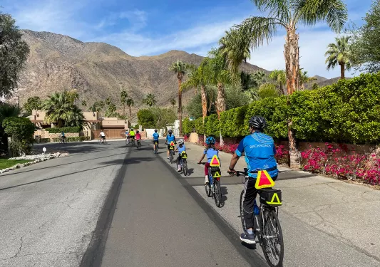 Group of guests riding single-file through a desert neighborhood.