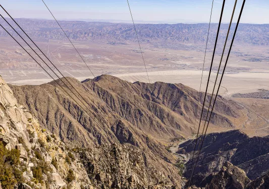 Wide shot of desert landscape, cables/wires in foreground.