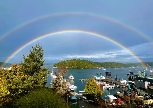 Wide shot of coastal port town, double rainbow across the sky.