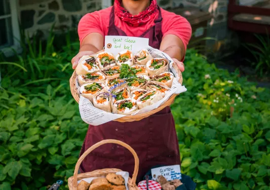Man holding cheese and beet wrap-platter up towards camera.