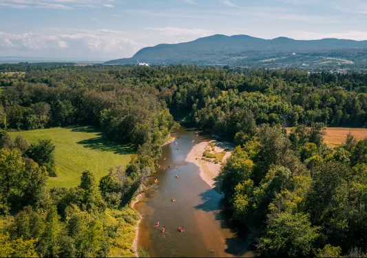 Bird's eye shot of a large river, kayaking guests are visible below.