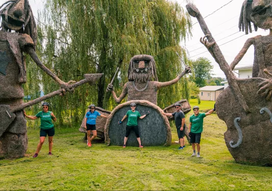 three guests posing with large wire and hay sculptures.