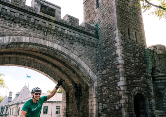 Guest riding under grey brick bridge.