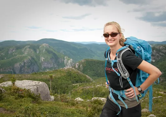 Guest smiling for camera, forested alpine mountain range in background.