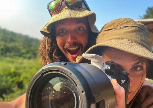 One person delighted standing behind another as she focuses camera