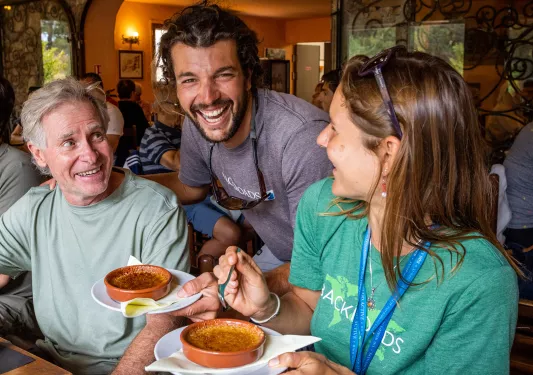 Two guests and leader at meal, guests have creme brulee.