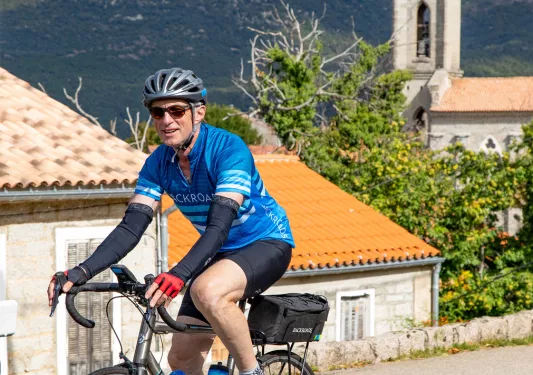 Guest cycling in Italian village, clock tower in background.