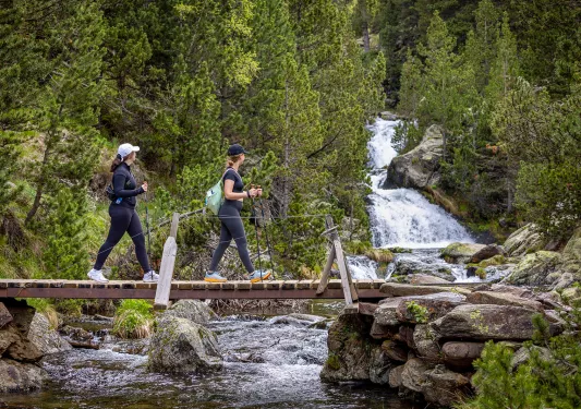 Hiking across a bridge with a waterfall in the background
