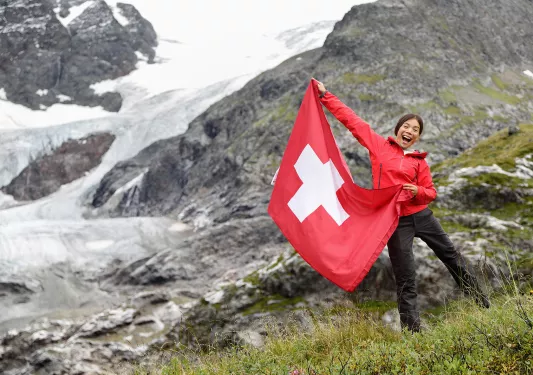 Guest/local on hillsides holding Swiss flag.