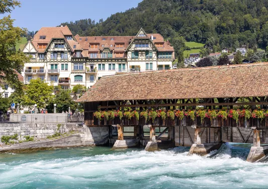 Bridge over the Aare River in Thun, Swiz. Large German style house in background.