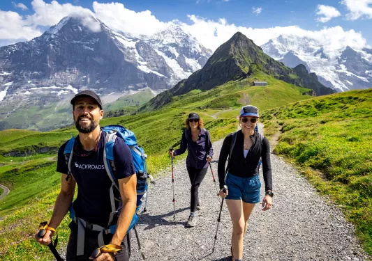 Three guests walking towards camera, Mount Eiger in background.