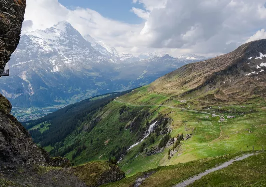 Wide shot of large mountain vista, small roads, hillsides, mountains in distance.