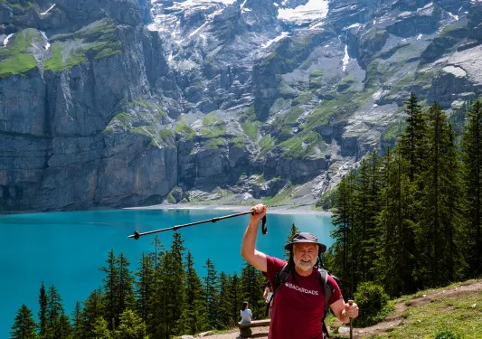 Guest raising pole in celebration, large mountains, lake in background. 