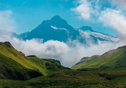 Valley view of Alpine mountains and clouds at the base.