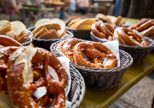 Multiple baskets of bread and pretzels.
