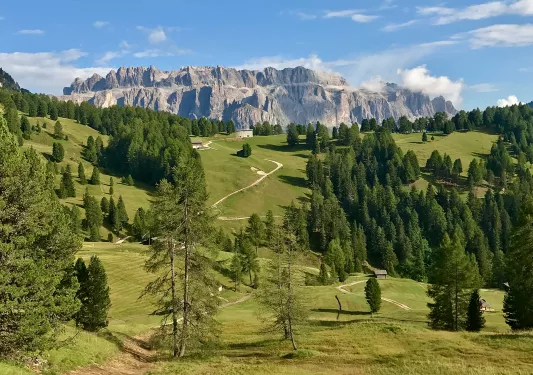 Wide shot of mountainous vista, small hilltop house in middleground.
