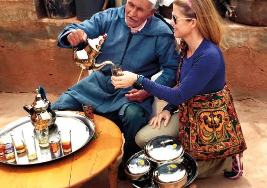 Guest with local, pouring tea.