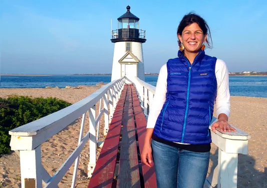 Shot of guest on thin pier, small lighthouse in background.