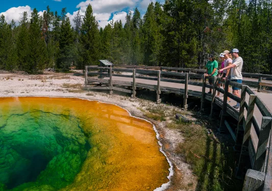 Backroads guests pointing at turquoise hot spring