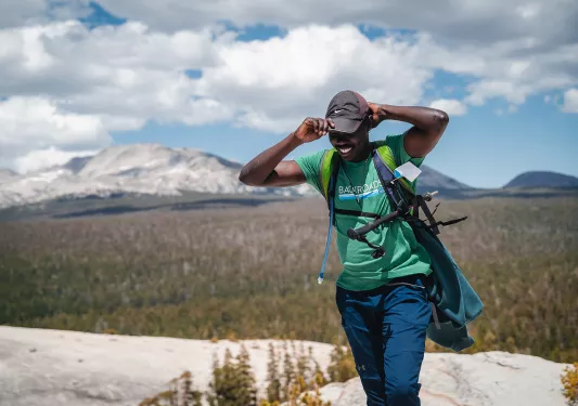 Guest/leader on mountaintop, forest floor in background. 