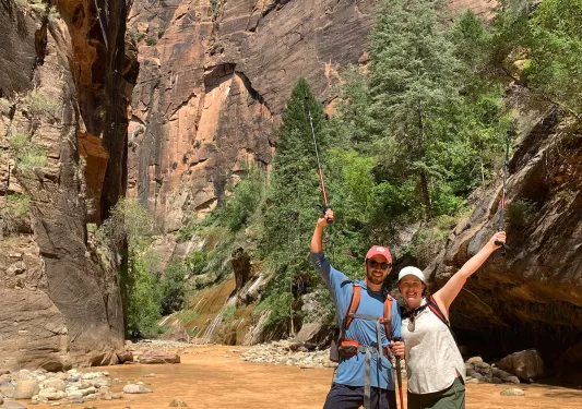 Hikers crossing stream with poles in the air