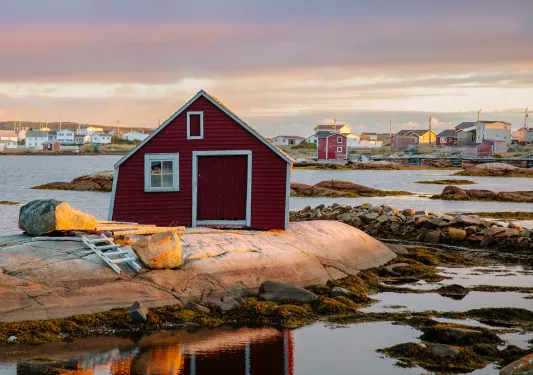 Rocky beach vista, numerous small houses in background, single red house wall in foreground.