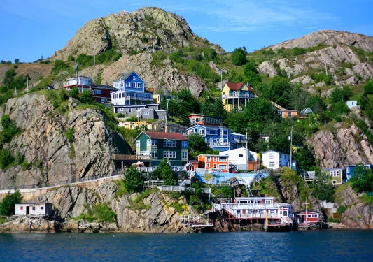 Wide shot of colorful coastal town in hillside. water below.