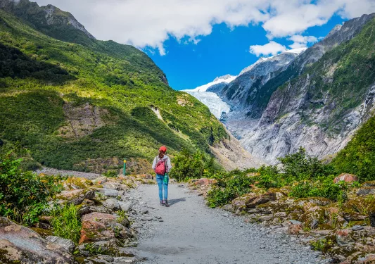Woman hiking on mountainous, glacial trail in New Zealand.