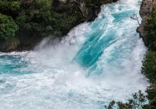 Wide shot of vibrant blue rushing waterfall.