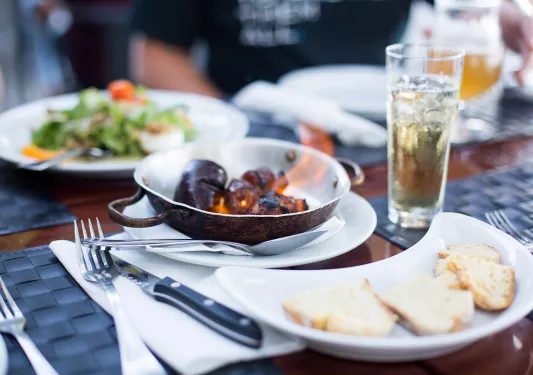 Close-up of dinner table, flaming plate of food, bread, salad on table.