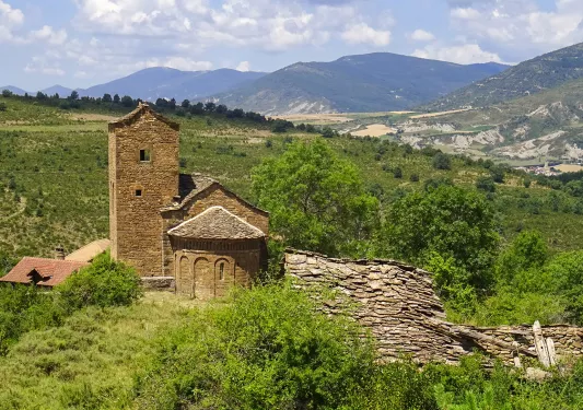Shot of old stone building in countryside, hilly vista in distance.